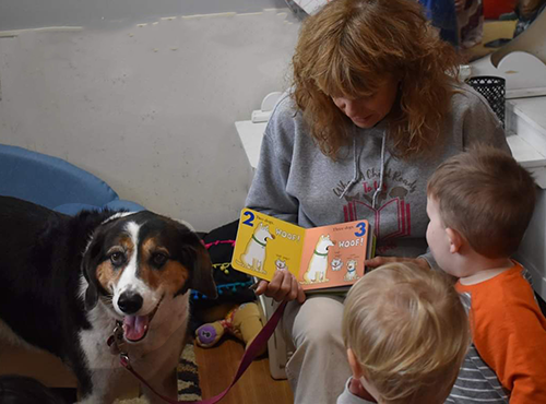 woman with dog reading to 2 small children