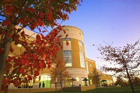 Picture of the front of the campus library with the trees turning orange for fall