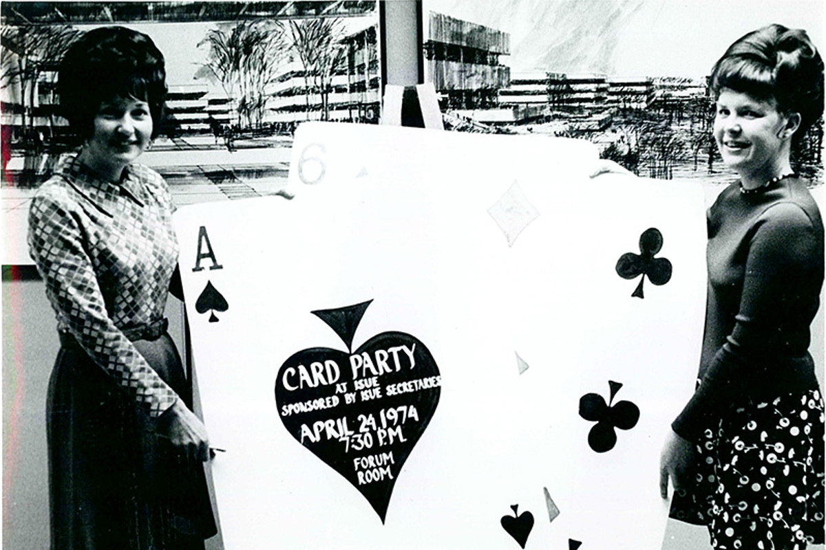 Mary Lue Russler (left) holds giant playing card invitation for an ISUE card party.