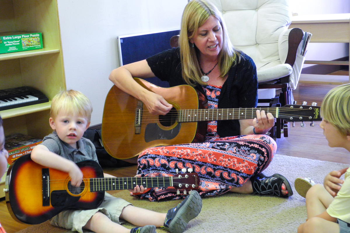 Ms. Karen strums and sings along with the children. They make up many new songs in the classroom.