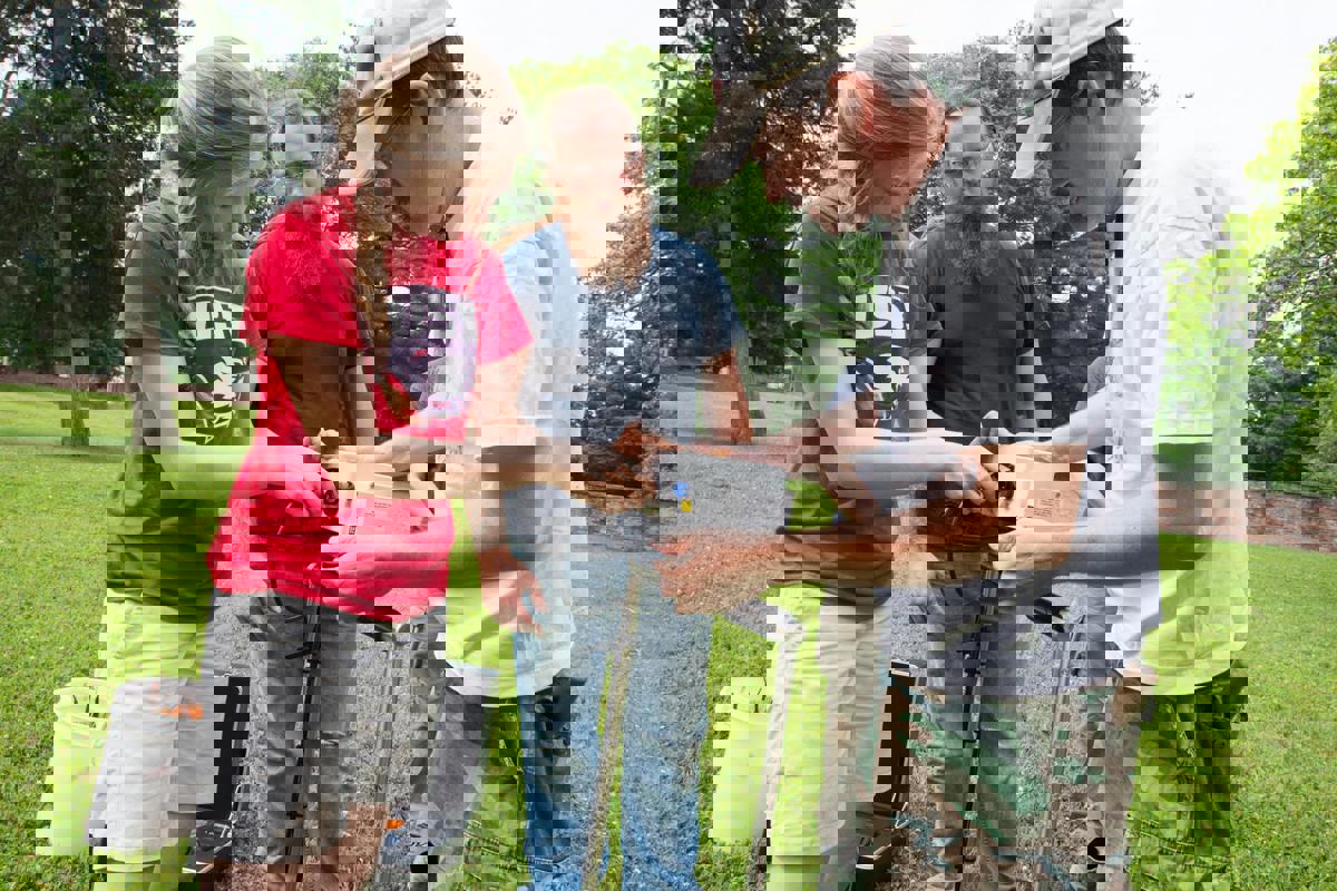 Dr. Michael Strezewski (right) shows Archaeological Field School students Abigail Krahling (left) and Andrew Schneider (center) how to use the program's new resistivity meter.