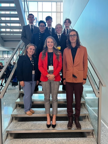 Eight USI students on stairs at conference