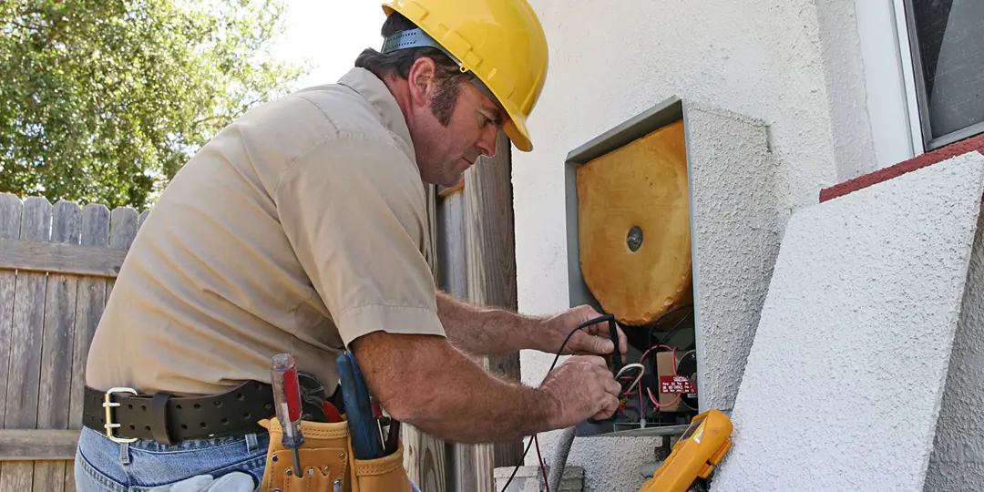 Man wearing a hard had and tool belt working on a residential utility