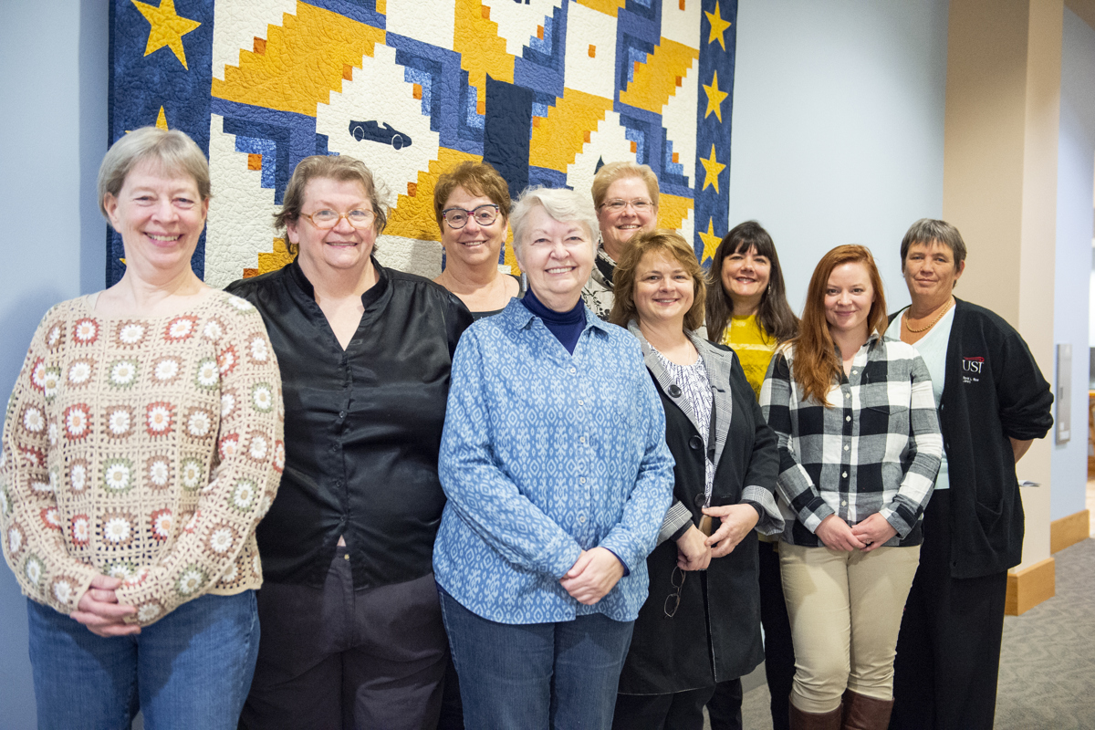 Members of the Raintree Quilters Guild of Evansville pose with USI archivist Jennifer Greene in front of the bicentennial quilt now hanging in David L. Rice Library