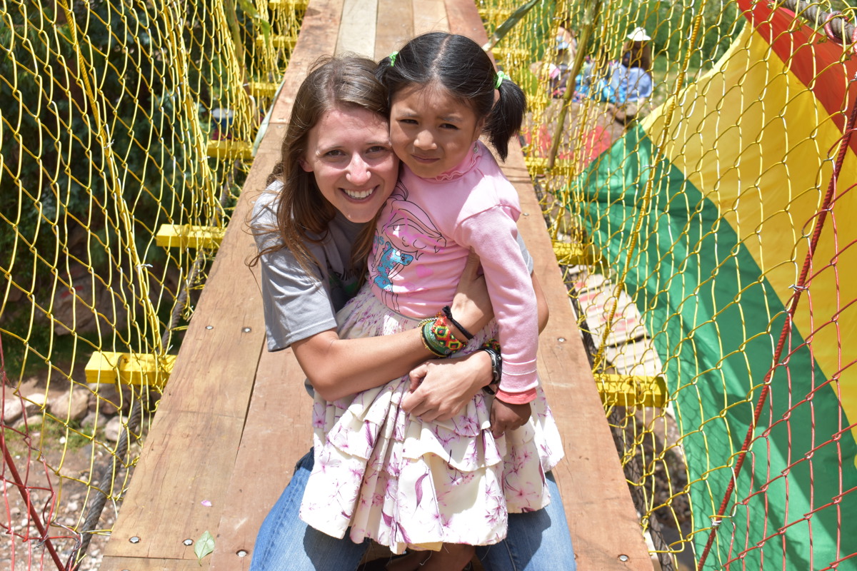 Holly Bartelt '12 poses with a young girl on a bridge created by Bridges to Prosperity in Bolivia 
