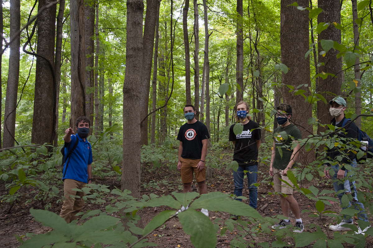 A guide points something out to students on a hike on a USI trail