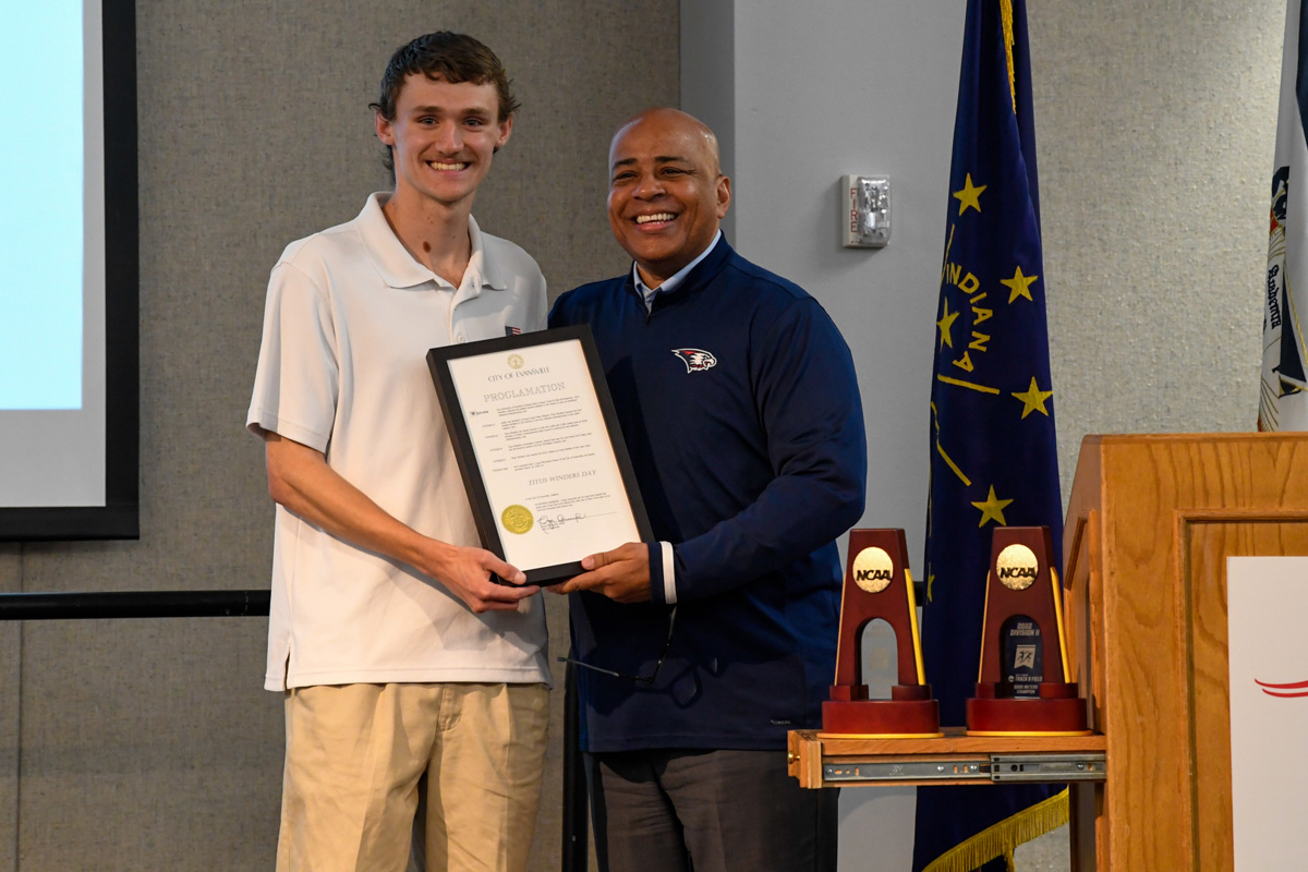 Titus Winders and President Rochon pose for a photo with the official proclamation and national championship trophies.