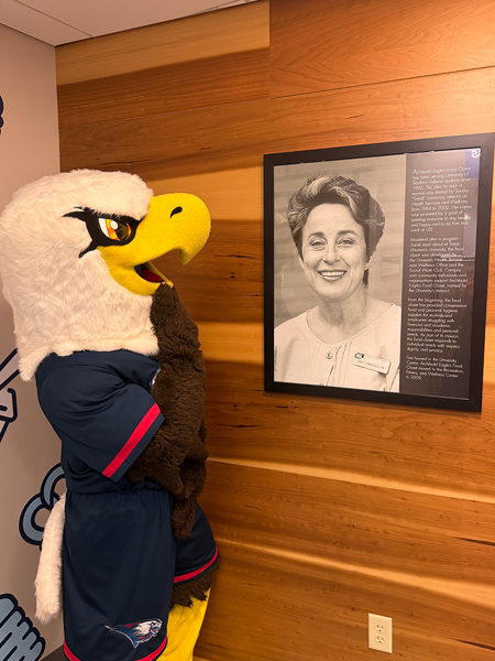 Archie by a framed photo of food pantry founder, Sandra Lawrence
