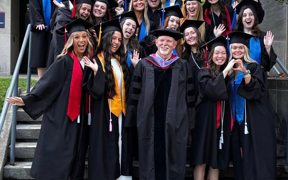 Students in caps and gowns pose with photo with Dr. Craig