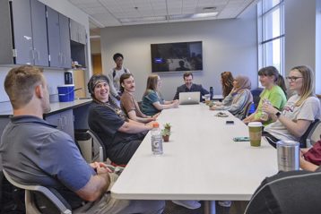 Students meeting for a research lab meeting at a long table in our Psychology research lab space