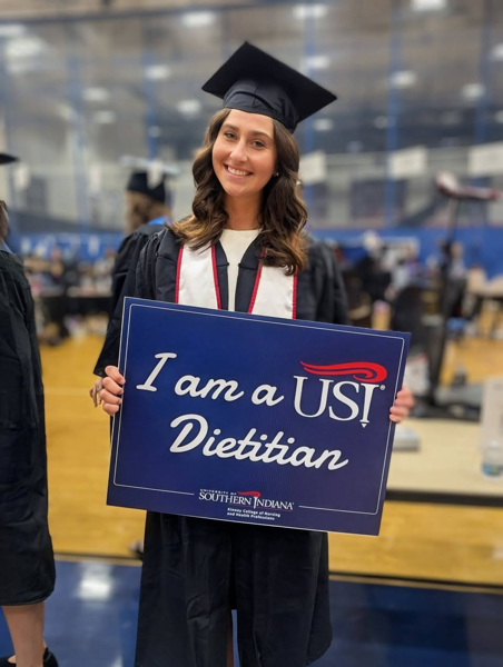 Graduate holding "I am a USI Dietitian" sign