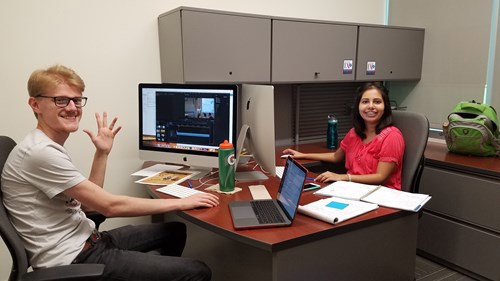 Luke and Reeya seated at their desk