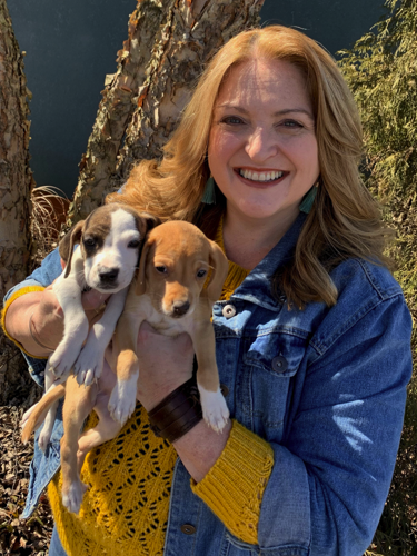 smiling woman holding 2 puppies