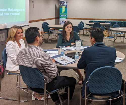 Four people seated around a table with binders and documents