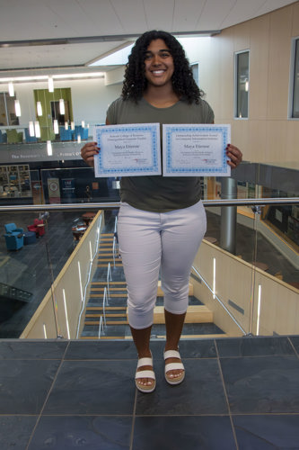 Maya holding both certificates
