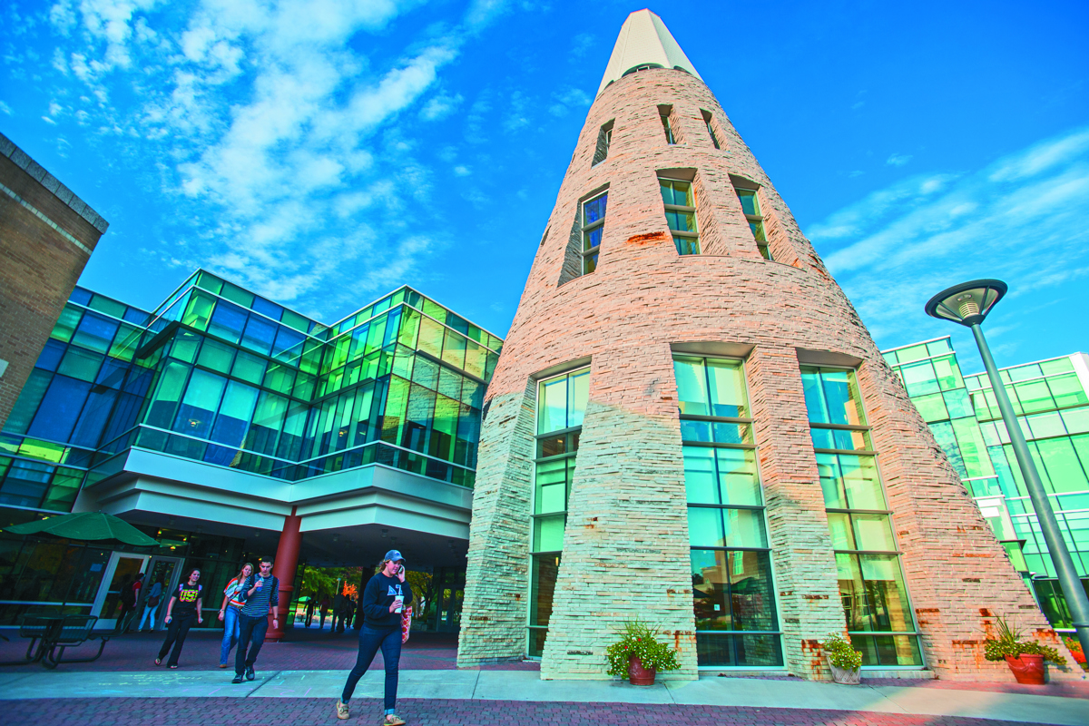 Students walk beside the Cone. The photo is shot from a low, ground angle. It's from the vantage point of looking up at the Cone.