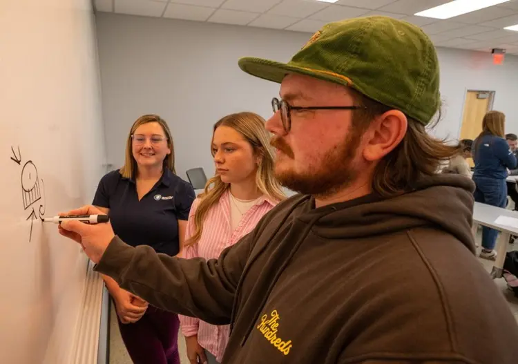 USI students collaborate at a whiteboard with AMCOR staff