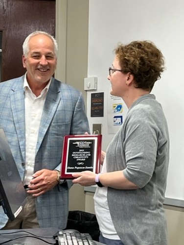 Dr. Popescu-Sandu Chair of the English Department being presented a Faculty Excellence Award by College of Liberal Arts Dean Del Doughty
