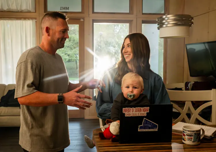 USI student with her husband and infant son in front of a laptop in their home