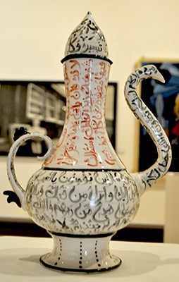 Image of a pitcher with a lid and curving spout