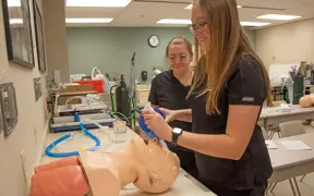 Students practice intubating a practice patient in a skills lab