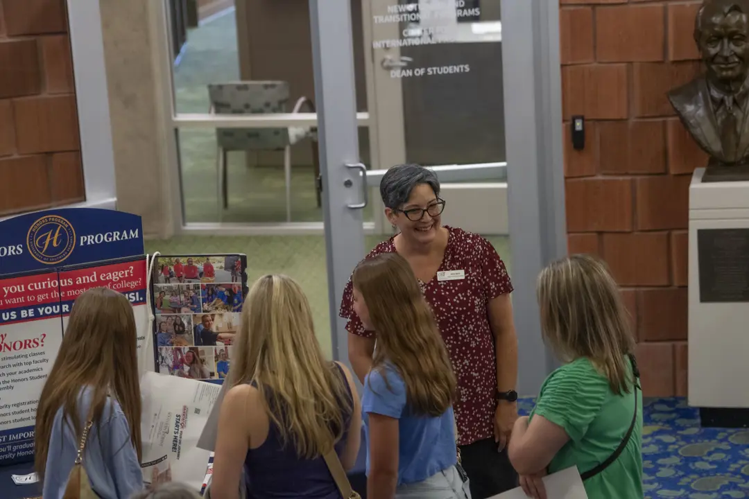 The Honors Program Director smiling while discussing with new students at USI's orientation. 