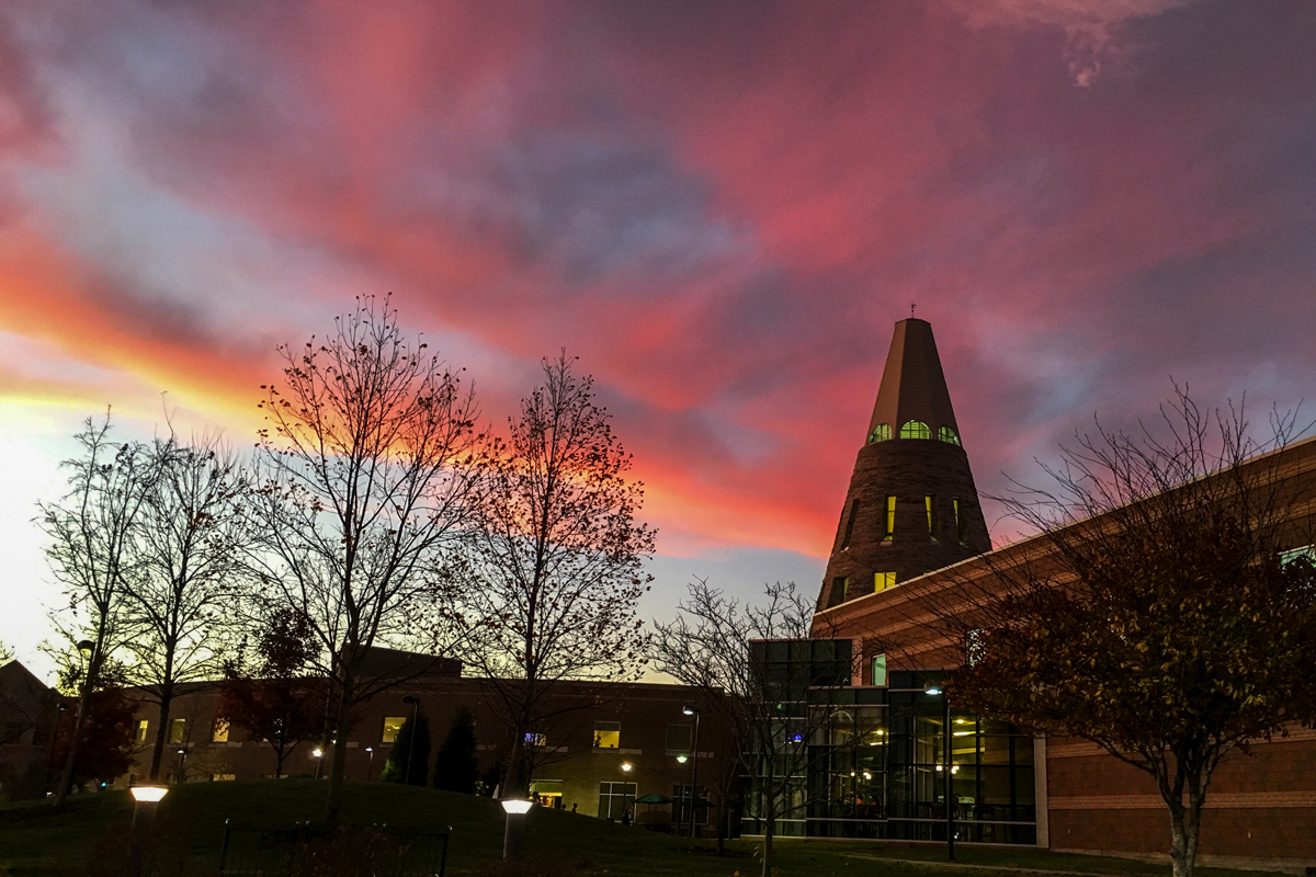 The Cone backlit with a pink and orange sunset on campus.