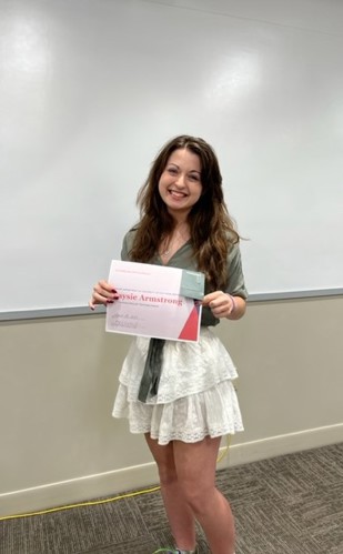 Caysie Armstrong posing with award at the English Awards Day Potluck